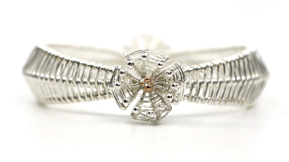 silver bracelet with central gold detail on white background