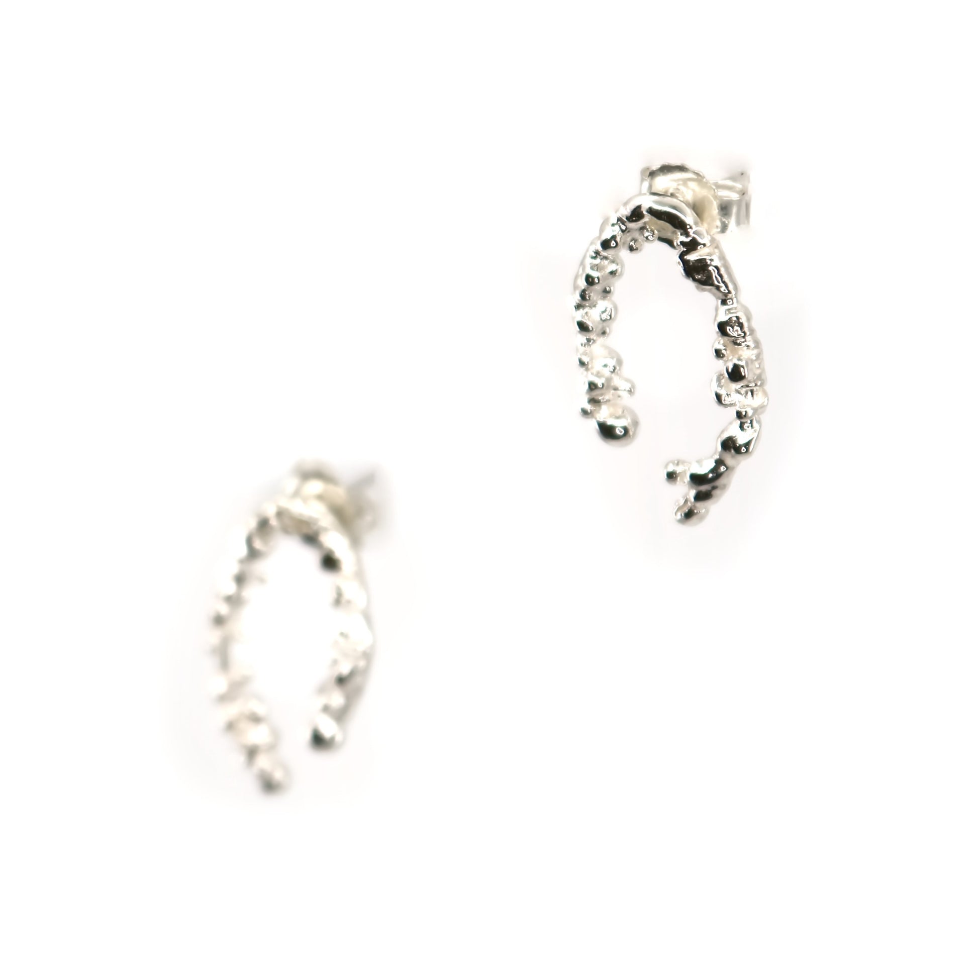Pair of horseshoe shaped silver earrings on a white background
