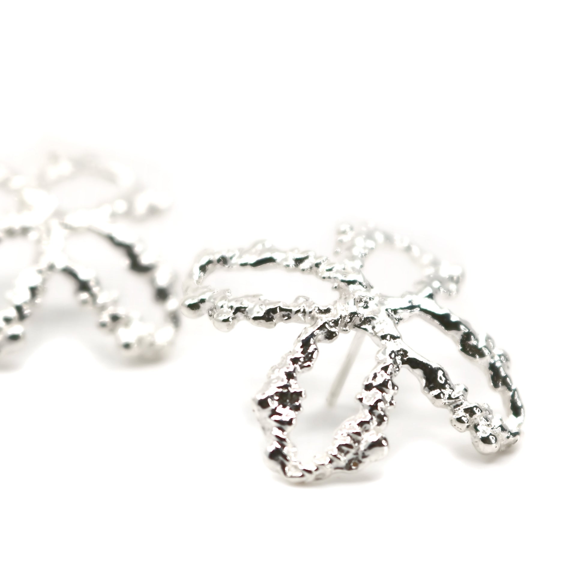 Silver earring with textured design on a white background